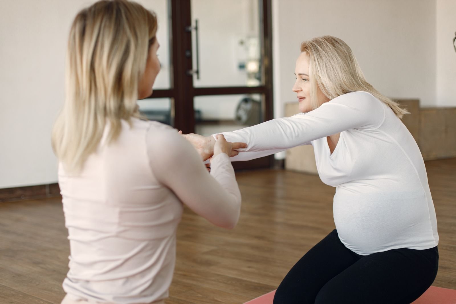 Physiotherapist supporting a pregnant patient through a guided standing exercise